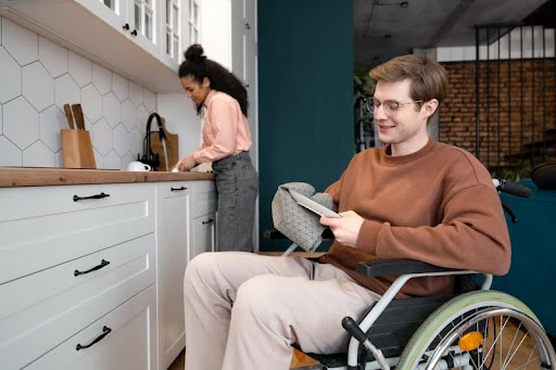 A wheelchair user in a kitchen with another person