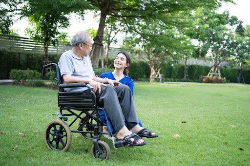 A woman walking alongside a wheelchair user outdoors